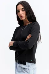 Remera de manga larga color negro, con silueta levemente boxy y largo a la cintura. Presenta una estampa lineal de una flor en el centro del pecho.