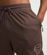 Bermuda deportiva masculina color marrón, confeccionada con tecnología Dry que evapora el sudor. Tiene cintura elástica con cordón ajustable y estampado de baloncesto.