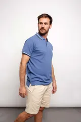 Remera tipo polo de hombre, color azul, con cuello y ribetes en las mangas con franjas blancas y azul marino.