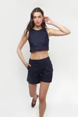 Top corto tipo halter de jean azul oscuro, con cuello a la base, pinzas delanteras para mayor estructura y pespuntes en color rojo. Cuenta con cierre lateral y abertura con botón en la espalda.