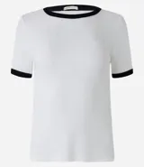 Blusa de manga corta, color blanco, con tejido de punto acanalado y ribetes contrastantes en color negro en el cuello redondo y en los bordes de las mangas.