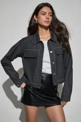 Campera de denim color negro con detalles de tachas metálicas en cuello, solapas, solapa de cierre y bolsillos frontales. Posee cierre frontal con botones metálicos y bolsillos con solapa en el pecho.