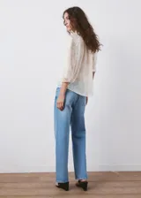 Blusa de tejido semitransparente color crudo, con diseño recto, cuello alto con volados, mangas largas abullonadas con puños abotonados y detalle de bordado floral en toda la prenda. Cuenta con cierre frontal de botones ocultos y ribete con volado en la botonera.