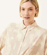 Camisa color beige con estampado geométrico, cuello camisero, manga larga y lazo frontal.