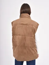 Chaleco acolchado de pana color marrón, diseño puffer sin mangas con cuello alto y cierre frontal de botones a presión.