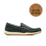 Mocasín de cuero negro estilo náutico, con costuras pespunteadas visibles, cordón decorativo lateral que pasa por ojalillos metálicos, suela de goma blanca y base caramelo con estriado antideslizante.