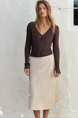 Falda corta tipo pareo, color marrón oscuro, confeccionada en tejido satinado con lazada ajustable en el lateral.