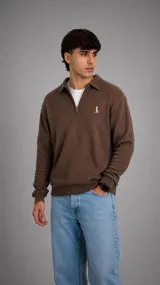 Buzo de punto color marrón con cuello polo y cierre frontal parcial. Presenta textura acanalada, mangas largas con puños elásticos y un pequeño bordado en el pecho.