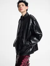 Chaqueta bomber negra de piel sintética con cierre frontal y cuello clásico.