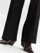 Pantalón wide leg de tiro alto con pinzas frontales. Confeccionado en tejido de punto interlock, presenta un diseño largo de calce amplio y textura firme.