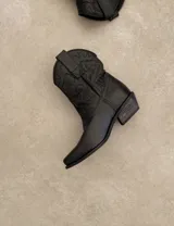 Bota corta estilo western de cuero color marrón, con taco cuadrado de 5 cm y diseño clásico. Presenta un acabado desgastado en la puntera y el talón.