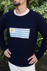 Sweater de lana azul marino, de corte clásico y cuello redondo, con diseño de la bandera de Uruguay bordado en el frente.