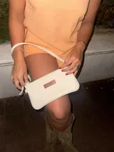 Mini cartera de cuero color crudo con correa larga extraíble y bolsillo interno con cierre.