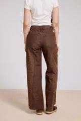 Pantalon de jean azul de corte ancho, con paneles laterales estampados con diseño floral sutil y costuras visibles.
