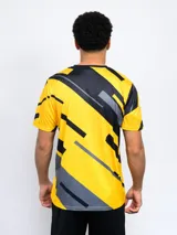 Remera de entrenamiento Fynar del Club Atlético Peñarol, color negro con estampado geométrico en amarillo y gris. Presenta cuello redondo, mangas cortas y el escudo del club en el pecho.