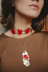 Gargantilla dorada con piedras rojas irregulares y colgante dorado con piedra roja irregular.