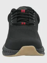 Sneaker de diseño deportivo con capellada de tejido knit negro, cordones al tono con detalle en rojo y suela con estructura tecnológica de amortiguación en color negro con base de goma clara.