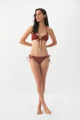 Conjunto de bikini color terracota con textura acanalada. El top es de estilo triangular con un detalle de abertura central y cordones ajustables. La bombacha es de corte clásico con tiras laterales para anudar.