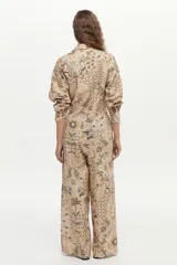 Camisa beige de manga larga, con cuello camisero, cierre frontal con botones y un estampado detallado de motivos botánicos e insectos en tonos oscuros.