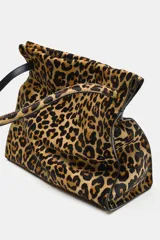 Bolso de hombro confeccionado en piel con estampado animal print de leopardo y textura. Cuenta con compartimento interior con cremallera, asa larga de hombro y cierre mediante botón imantado.