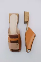 Mules de cuero color beige con detalles en marrón y suela de madera.