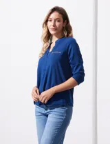 Blusa azul con cuello a la base y escote en V. Tiene bolsillos con cierre metálico.