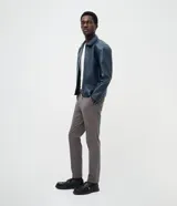 Pantalón slim de sarga lavada color marrón, con cierre de botón y cremallera, trabillas para cinturón y bolsillos laterales y traseros.
