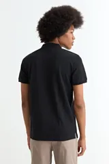 Remera tipo polo de manga corta, color negro, con cuello clásico y cierre frontal de tres botones.