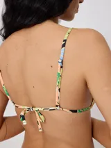 Top de bikini triangular con estampado tropical de flores azules y hojas verdes sobre fondo naranja y crema. Cuenta con tiras finas para atar en el cuello y la espalda.