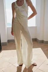 Pantalón de pierna ancha y tiro medio, confeccionado en tejido con textura arrugada. Presenta una cintura elástica destacada por un detalle de tejido en crochet a tono.
