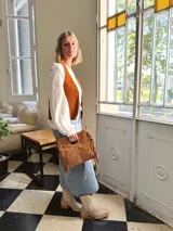 Cartera bandolera de cuero color camel, con forro interno de tela y flecos laterales.