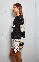 Sweater tejido de lana con diseño de rayas horizontales en blanco y negro, y aplique de un mono en el centro. Tiene cuello redondo y puños ajustados con detalles bordados.