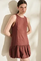 Vestido corto de lino color bordó, sin mangas, con escote redondo, costuras decorativas con flecos y falda estilo globo con volados en el ruedo.