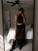 Pollera larga de encaje negro con diseño floral, presenta una abertura lateral pronunciada y cintura elástica.