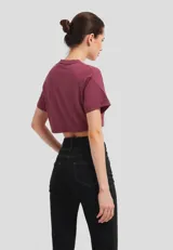 Remera cropped de algodón, color gris claro, con cuello redondo y manga corta doblada. Presenta un estampado frontal de un plátano amarillo.