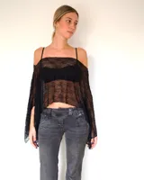 Capa de encaje negro con diseño asimétrico y caída holgada, ideal para usar sobre otras prendas.