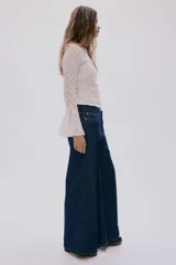 Jean de cinco bolsillos en denim rígido, de corte wide leg y tiro regular, con piernas amplias y costuras en contraste.