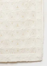 Falda midi de corte recto con diseño calado y flores en relieve. Presenta tiro medio, abertura lateral en el bajo y cierre de cremallera lateral. Incluye forro interior.