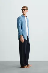 Camisa de corte regular fit confeccionada en tejido de lino, con cuello solapa, manga larga con puños abotonados y cierre frontal de botones.