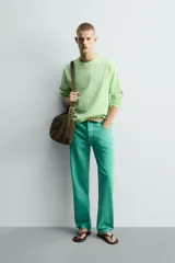 Jeans de mezclilla de corte recto, tiro medio, color verde vibrante con efecto lavado. Presenta cierre frontal con cremallera y botón, y cinco bolsillos.