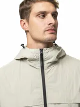 Campera rompevientos de nylon color gris, con capucha ajustable, cierre frontal completo, bolsillos laterales con cierre, puños elásticos y ruedo ajustable.