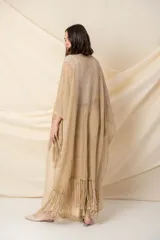 Poncho artesanal color beige con hilos de lurex dorados y terminación de flecos. Diseño irregular, más corto adelante que atrás.