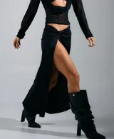 Pollera maxi negra con diseño drapeado en la cintura y una pronunciada abertura frontal que deja al descubierto la pierna. Confeccionada en tela elástica y moldeadora que se ajusta a la silueta.
