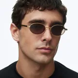 Lentes de sol con montura ovalada de acero inoxidable en color dorado y cristales polarizados en tono marrón. Presentan un diseño minimalista con patillas de acetato negro.