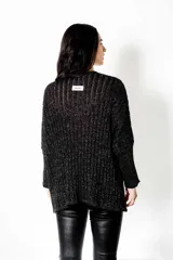 Poncho tejido en Lurex negro con hilos plateados brillantes, escote en V y mangas largas. Presenta un calce suelto y relajado.