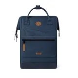 Mochila Cabaia modelo Adventurer Reykjavik, color azul con detalles en marrón. Tiene sistema MOLLE, compartimento acolchado para tablet o PC, correa para sujetar a la maleta y tirantes acolchados antitranspirantes. Vegana e impermeable.