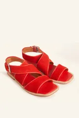 Sandalias bajas de cuero negro con tachas plateadas, tiras cruzadas y hebilla al tobillo.