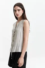 Blusa sin mangas color gris claro con textura rayada vertical y lazo ajustable en el escote.