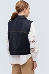 Chaleco de denim azul marino con cuello, bolsillos frontales y bordes festoneados.