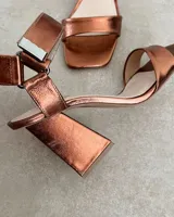 Sandalia de taco cuadrado alto, con diseño de punta cuadrada, tira delantera ancha y tira ajustable en el tobillo con hebilla metálica.
